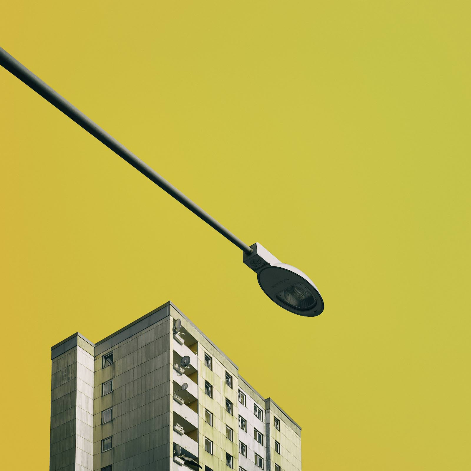 Wohnhaus und Straßenlampe vor gelbem Hintergrund