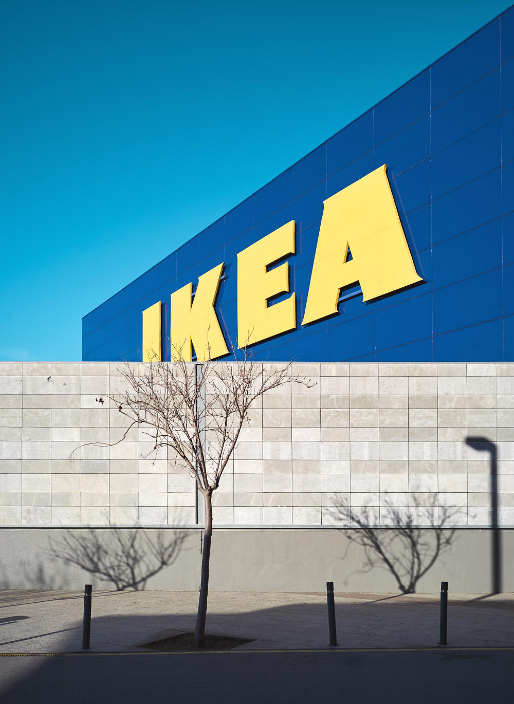 Blick auf eine Mauer, mit Schattenspiel und Ikea Warenhaus im Hintergrund