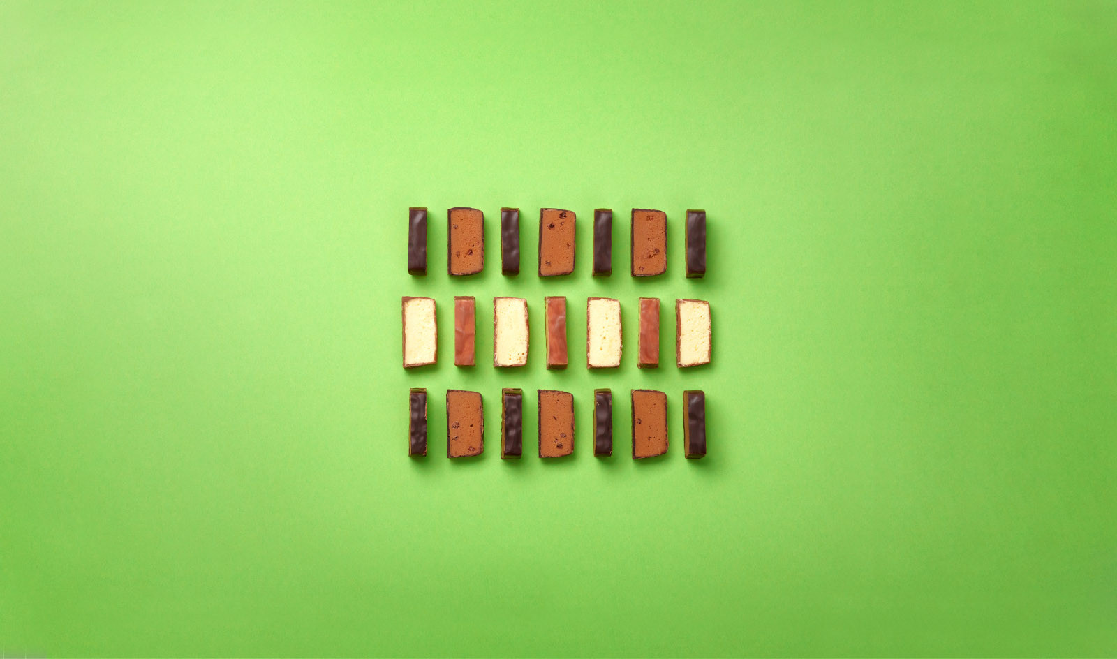 Schokoladenstücke arrangiert auf grünem Untergrund, fotografiert von oben