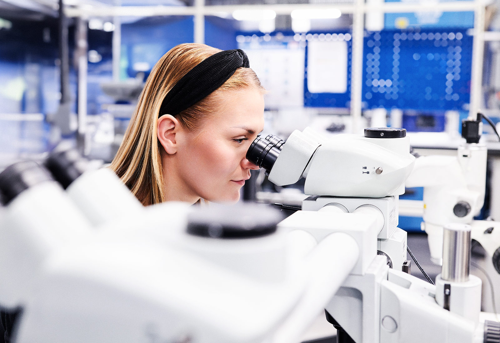 Frau mit Blick durch ein Mikroskop bei SECO Tools in Schweden