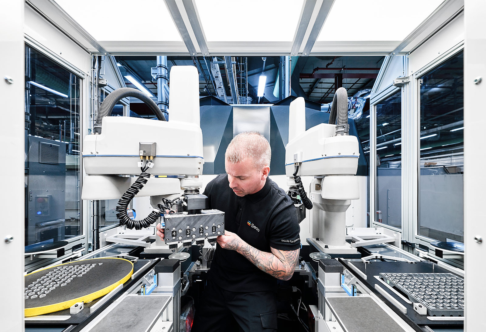 Person kontrolliert den Arm eines Roboters in einer automatisierten Produktionsanlage