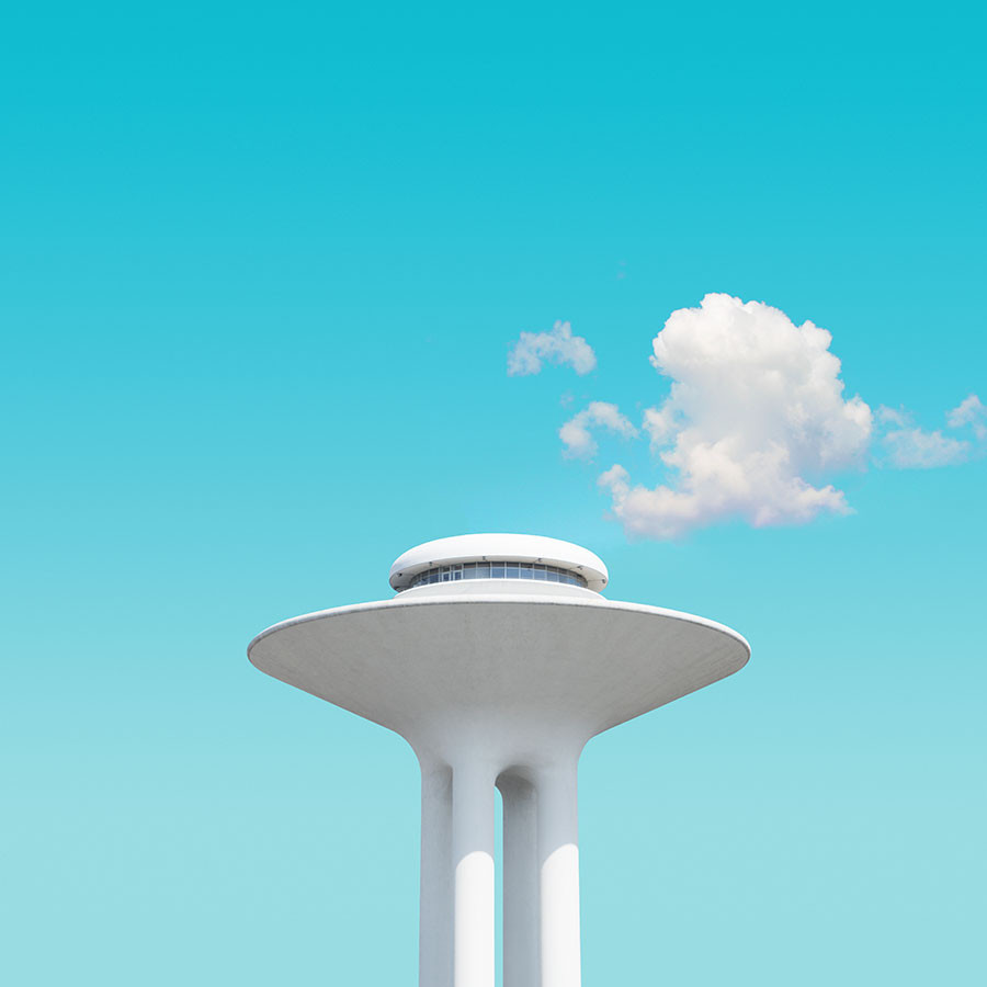 Turm der die Anmutung einer UFO-Scheibe hat, mit einer Wolke darüber.