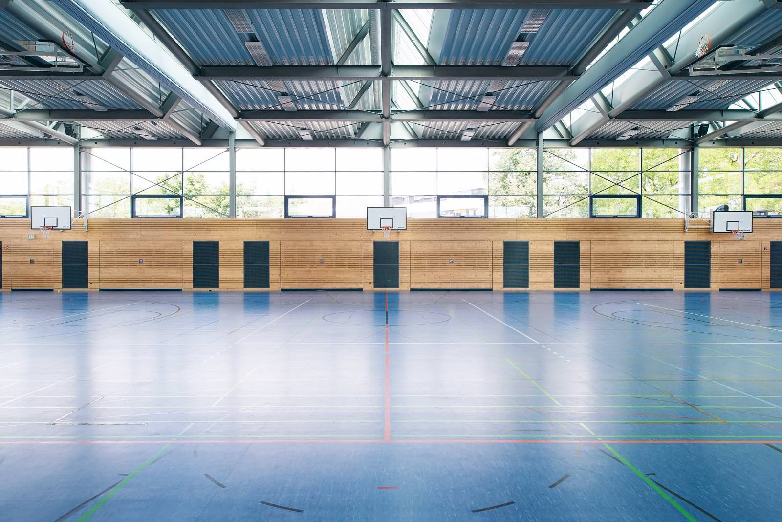 Blick eine Turnhalle entlang mit Basketball Körben im Hintergrund