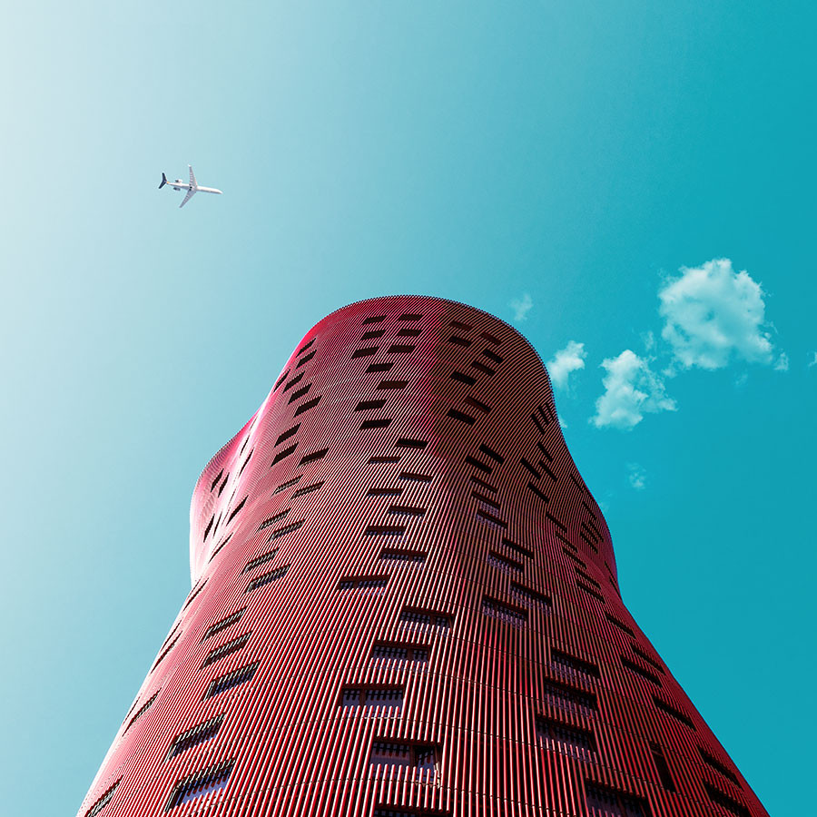 Architekturaufnahme, Blick eine rote Fassade hinauf, mit Flugzeug im Himmel
