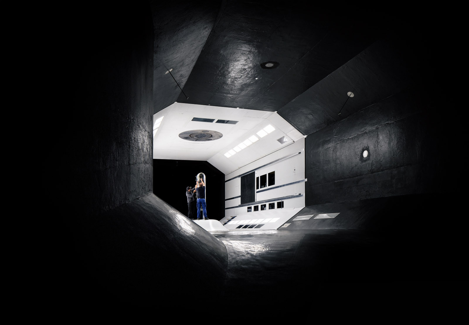 Seitenansicht des Windtunnels mit zwei Personen bei der Arbeit