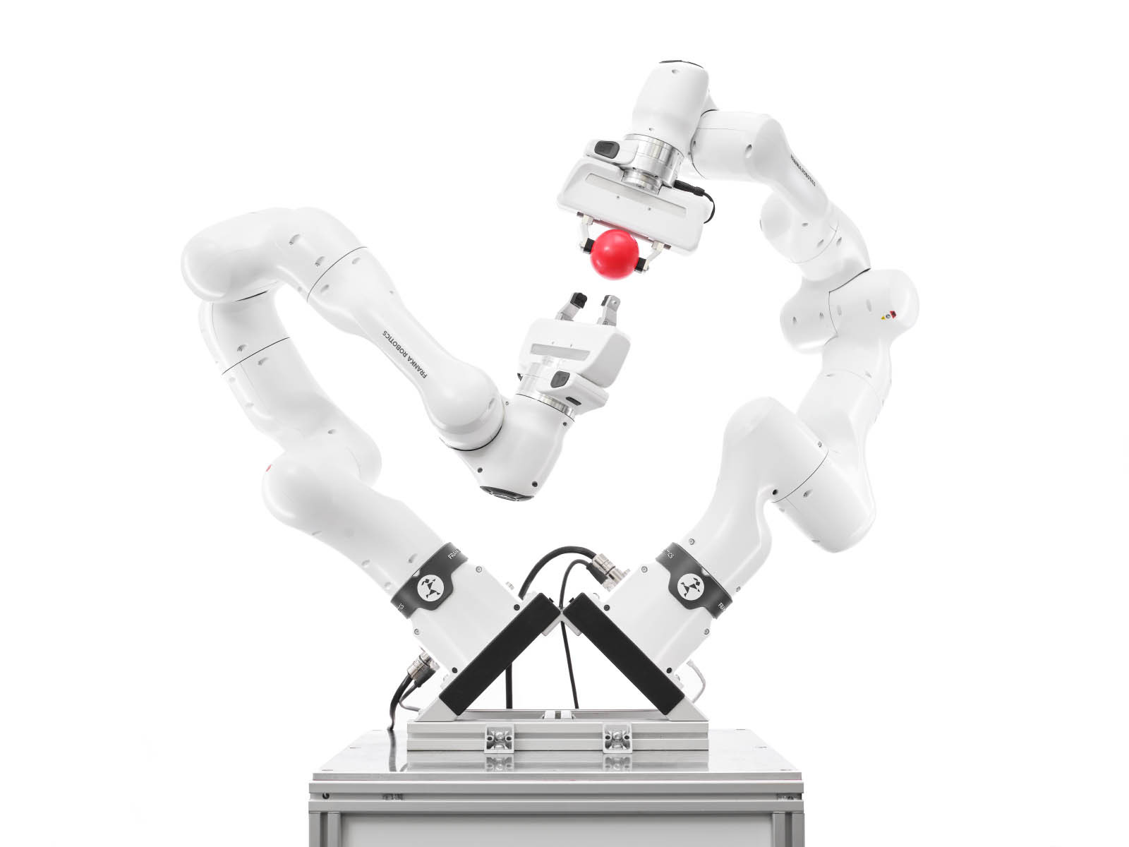 Zwei Franka Roboter im Dialog miteinander, einer der Roboter übergibt einen Ball an den anderen.