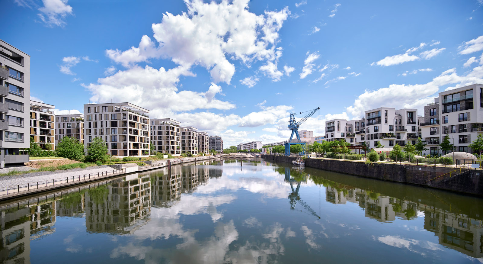 Ansicht der Wohngebäude von einer Verbindungsbücke aus, mit Spiegelungen im Wasser