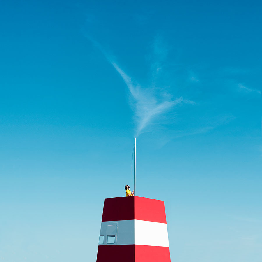 Person ist Dabei ein Flagge an einem Mast aufzuhängen. Viel Himmel im Bild.